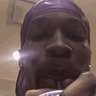a close up of a person 's face with a purple headband on .