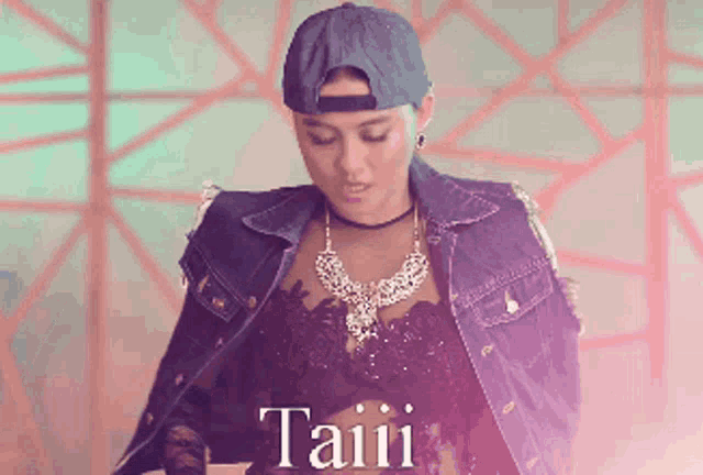 a woman wearing a denim jacket and a baseball cap with the word taiii on the bottom right