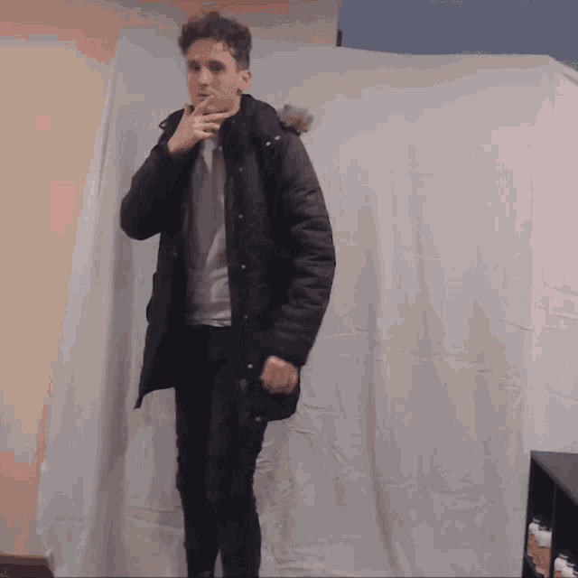 a young man wearing a black parka with a fur hood