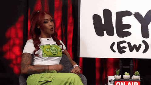 a woman sitting in front of a sign that says hey ew