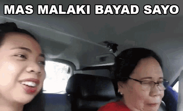 two women are sitting in a car with the words mas malaki bayad sayo written above them