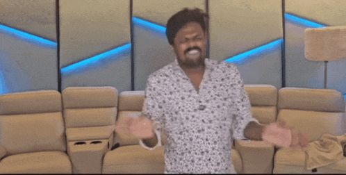 a man standing in front of a couch making a funny face