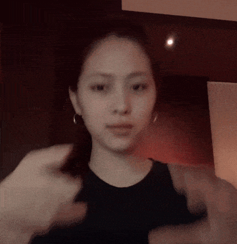 a woman wearing a black tank top and earrings is making a funny face