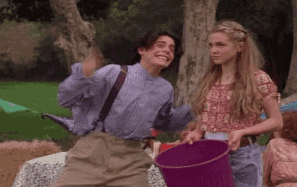 a boy and a girl are standing next to each other holding a purple bucket