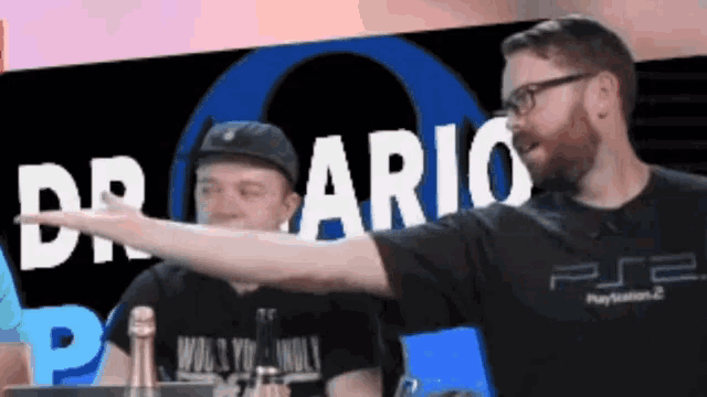 a man wearing a playstation 2 shirt is pointing at something