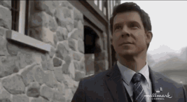 a man in a suit and tie is standing in front of a building that says hallmark channel on it