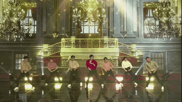 a group of men are dancing on a stage in front of a large building