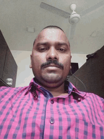 a man with a beard and mustache is wearing a pink and blue checkered shirt