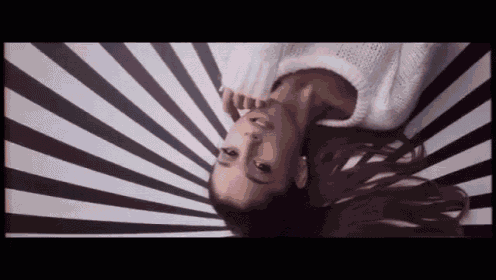 a woman is laying on her back on a black and white striped background .