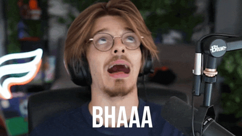 a man wearing glasses and headphones says bhaaa in front of a microphone
