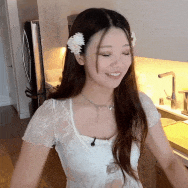 a woman with a flower in her hair stands in front of a refrigerator