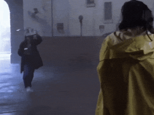 a woman in a yellow raincoat is standing in the rain