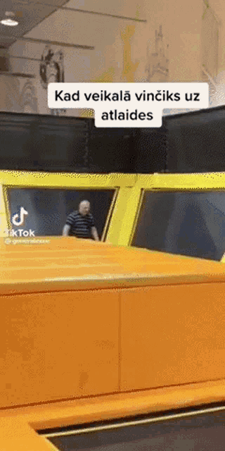 a man is jumping on a trampoline with a caption that says `` kad veikala vinciks uz atlaides '' .