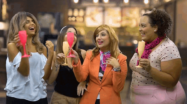 a group of women are holding champagne glasses and laughing