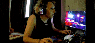 a man wearing headphones is sitting in front of a computer screen .