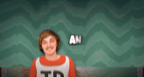 a man wearing a shirt that says jp is smiling in front of a green background