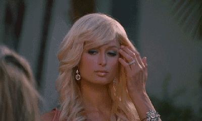 a close up of a blonde woman wearing earrings and a pink top