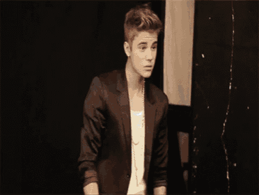 justin bieber is wearing a black suit and a white shirt .