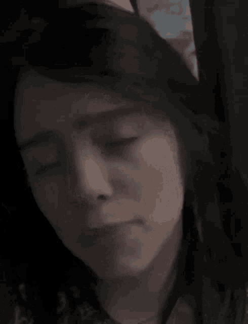 a close up of a woman 's face with her eyes closed in a dark room .