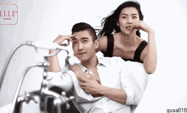 a woman sits on a man 's shoulders in a bathtub with a sign that says elle models