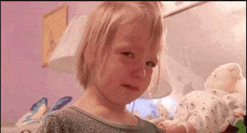 a little girl crying while holding a stuffed animal