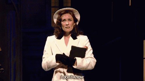a woman in a white coat and hat is standing on a stage holding a clipboard .