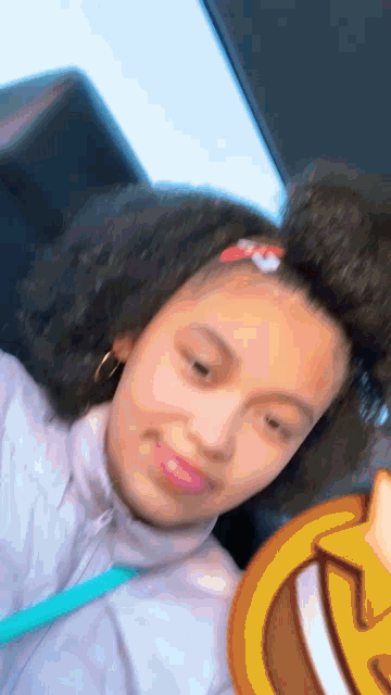 a young girl is taking a selfie in a car with a smiley face on her face .