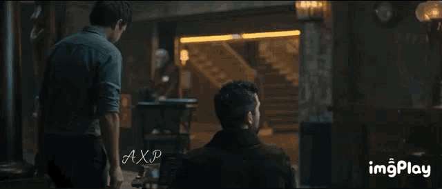 a man sitting in a dark room with the word axp on the bottom left