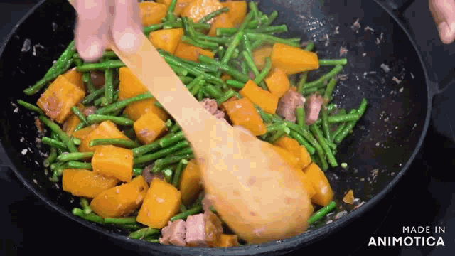a person is stirring vegetables in a pan with the words made in animotica on the bottom