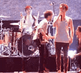 a man singing into a microphone while another man plays drums
