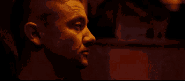 a man is wearing boxing gloves in a dark room and kissing another man .