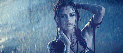 a woman is standing in the rain holding her hair