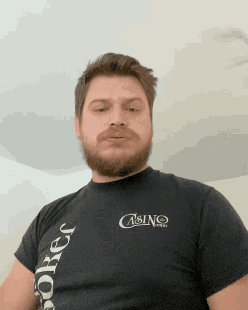 a man with a beard wears a black t-shirt that says casino