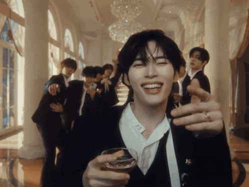 a group of men are standing in a hallway and one of them is holding a glass of alcohol