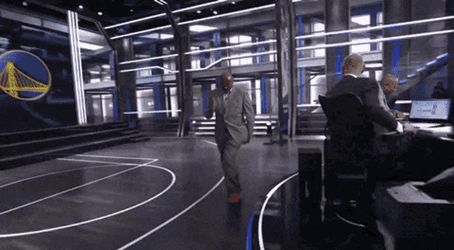 a man in a suit is dancing in front of a golden state warriors logo on the wall