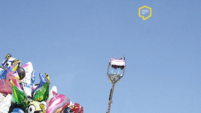 a bunch of balloons are stacked on top of each other with a ferris wheel in the background