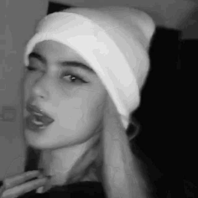 a black and white photo of a woman wearing a hat .