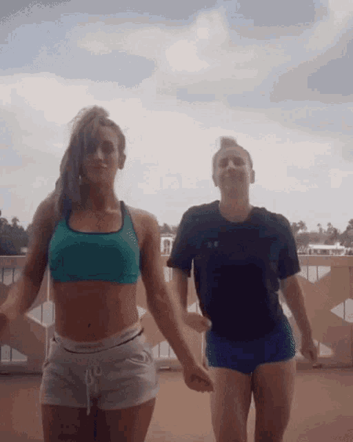 two women are dancing on a balcony and one is wearing a calvin klein shirt