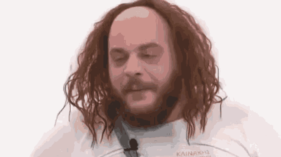 a bald man with long red hair and a beard is wearing a white shirt that says kainaki