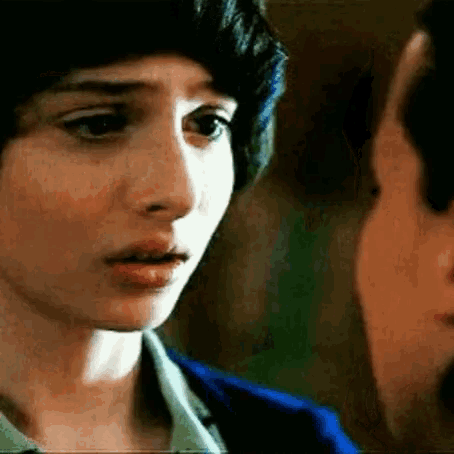 a close up of a woman 's face with a man 's face in the background .