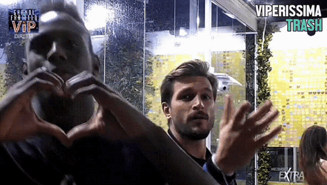 two men are making a heart shape with their hands in front of a sign that says vip extra
