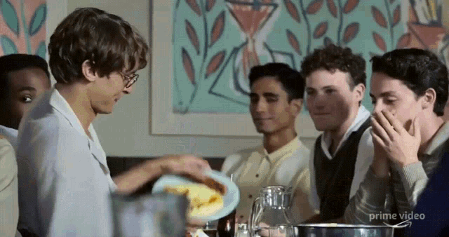 a group of young men are sitting around a table with a sign that says prime video in the corner
