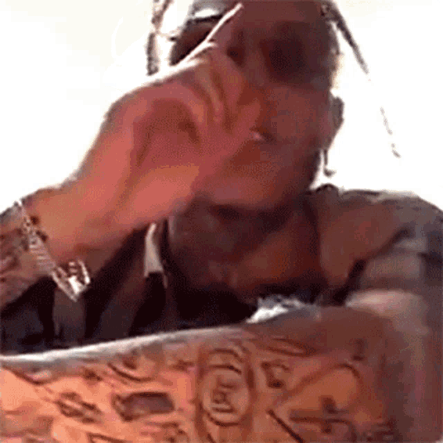 a man with a tattoo on his arm is smoking a cigarette while sitting at a table .