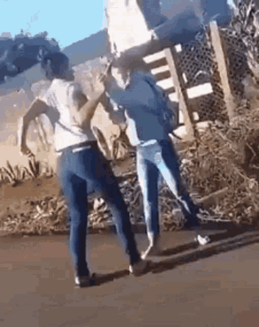 two women are standing next to each other on a street .