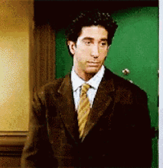 a man in a suit and tie stands in front of a green door
