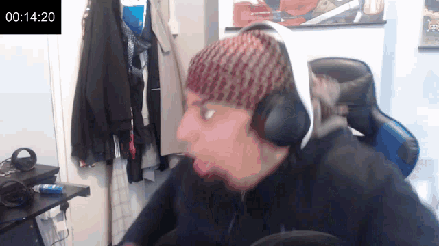 a man wearing headphones and a beanie is sitting in front of a timer that reads 00:14