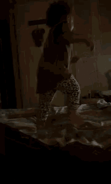 a child is jumping on a bed in a dark room .