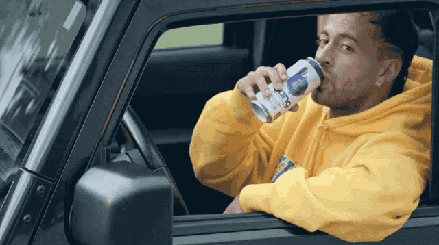 a man in a yellow hoodie is drinking from a can that says ice