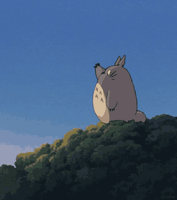 a cartoon totoro is sitting on top of a hill