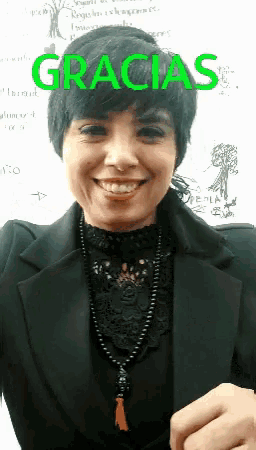 a woman is smiling in front of a white board that says gracias on it